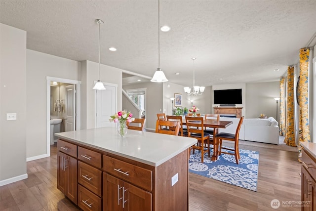 301 K St NE, Quincy, WA 98848 - kitchen with a textured ceiling, wood finished floors, decorative light fixtures, a kitchen island, and light countertops