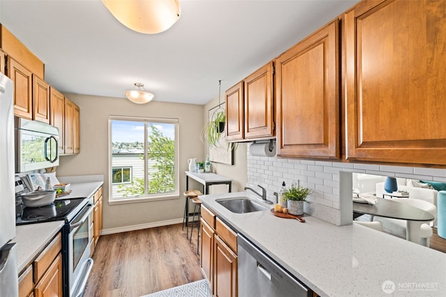 1965 12th Ave W Unit 202, Seattle, WA 98119 - kitchen with stainless steel appliances, a sink, light wood-type flooring, baseboards, and backsplash