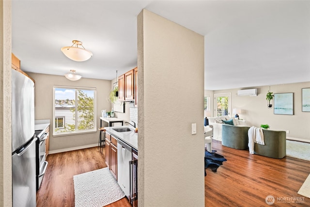 1965 12th Ave W Unit 202, Seattle, WA 98119 - kitchen with appliances with stainless steel finishes, a wall mounted air conditioner, wood finished floors, a sink, and light countertops