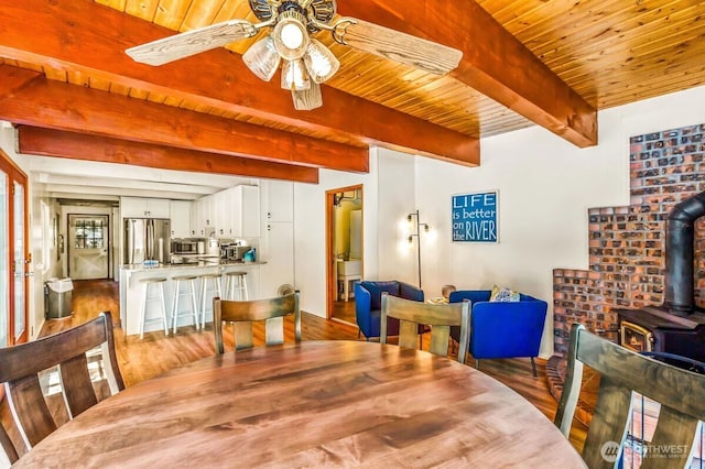 11318 583rd Ave E, Enumclaw, WA 98022 - dining space with a wood stove, wood finished floors, wood ceiling with exposed beams, and a ceiling fan