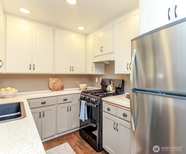 13812 Golden Given Rd E, Tacoma, WA 98445 - kitchen featuring appliances with stainless steel finishes, under cabinet range hood, light countertops, dark wood-style flooring, and recessed lighting