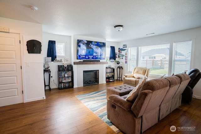 733 K St NE, Quincy, WA 98848 - living room featuring hardwood / wood-style floors, a glass covered fireplace, a textured ceiling, and baseboards