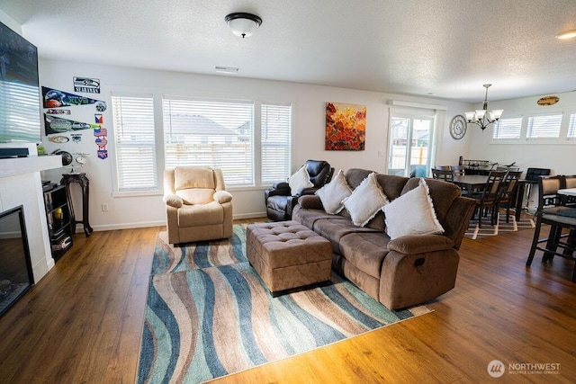 733 K St NE, Quincy, WA 98848 - living area with a chandelier, wood finished floors, a textured ceiling, a large fireplace, and baseboards