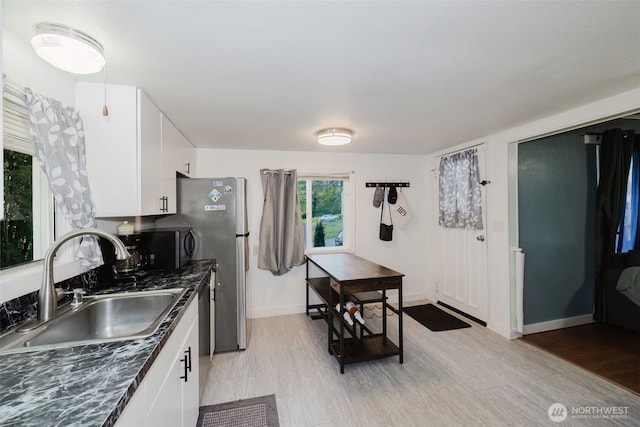 2395 SE Salmonberry Rd, Port Orchard, WA 98366 - kitchen with a sink, dark countertops, white cabinets, and light wood-style flooring