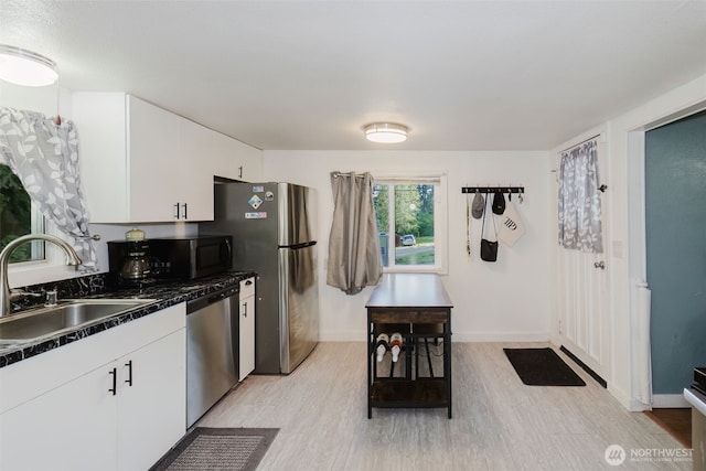 2395 SE Salmonberry Rd, Port Orchard, WA 98366 - kitchen featuring appliances with stainless steel finishes, a sink, light wood-type flooring, dark countertops, and white cabinetry