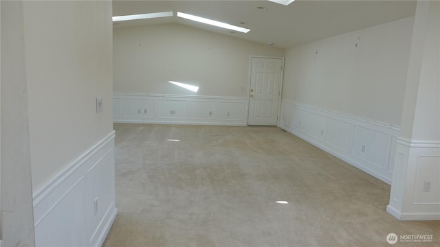 4635 N Defiance St, Tacoma, WA 98407 - empty room featuring a decorative wall, vaulted ceiling, carpet floors, a wainscoted wall, and a skylight