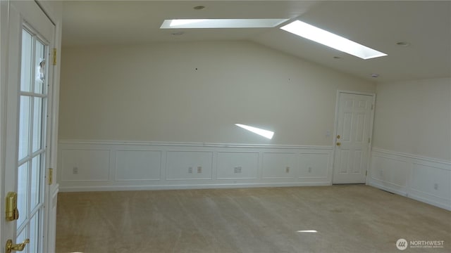 4635 N Defiance St, Tacoma, WA 98407 - spare room with a skylight, light colored carpet, vaulted ceiling, wainscoting, and a decorative wall