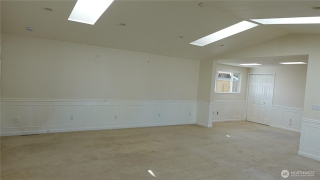 4635 N Defiance St, Tacoma, WA 98407 - spare room featuring a skylight, a decorative wall, light colored carpet, wainscoting, and vaulted ceiling