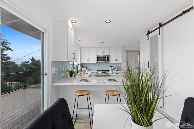 1345 Rainbow Ln, Camano Island, WA 98282 - kitchen with stainless steel appliances, tasteful backsplash, light countertops, white cabinetry, and a breakfast bar area