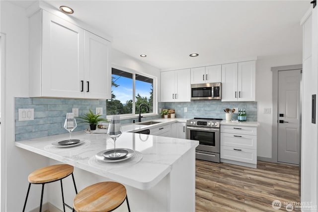 1345 Rainbow Ln, Camano Island, WA 98282 - kitchen with stainless steel appliances, a sink, light stone countertops, a peninsula, and white cabinetry