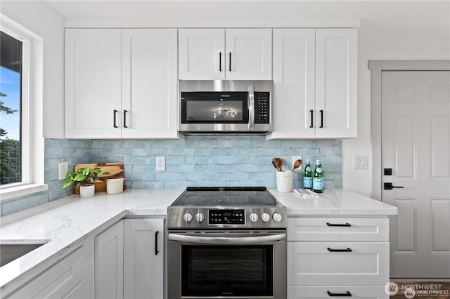 1345 Rainbow Ln, Camano Island, WA 98282 - kitchen with appliances with stainless steel finishes, white cabinetry, decorative backsplash, and light stone countertops