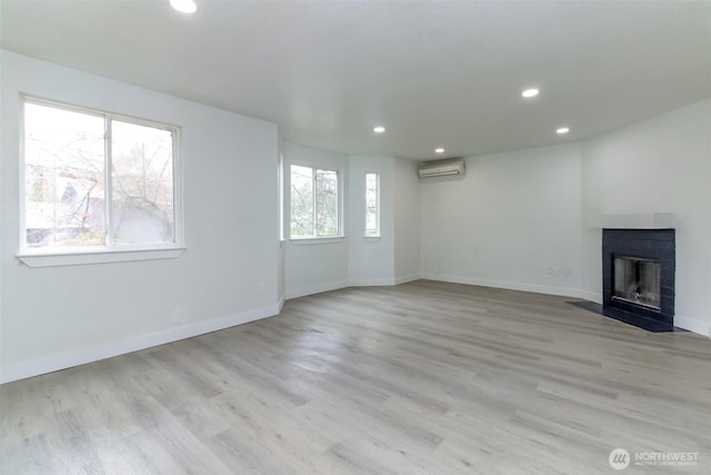 5611 S Cheyenne St, Tacoma, WA 98409 - unfurnished living room with a wall mounted air conditioner, recessed lighting, a fireplace with flush hearth, light wood finished floors, and baseboards