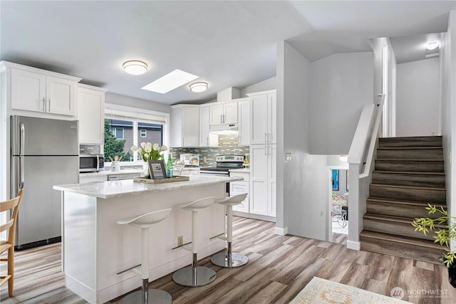 2 199th Pl SE, Bothell, WA 98012 - kitchen with appliances with stainless steel finishes, vaulted ceiling, backsplash, white cabinets, and light wood-style flooring