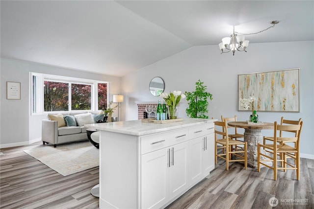 2 199th Pl SE, Bothell, WA 98012 - kitchen featuring vaulted ceiling, wood finished floors, a chandelier, a fireplace, and white cabinetry