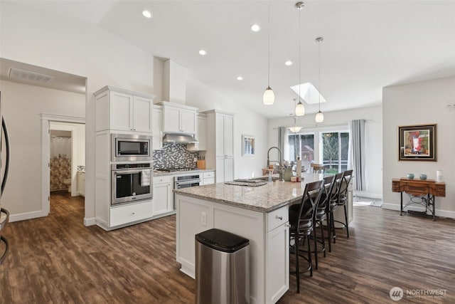 1172 Matterhorn Loop, Camano Island, WA 98282 - kitchen featuring stainless steel appliances, a kitchen breakfast bar, white cabinets, dark wood finished floors, and vaulted ceiling