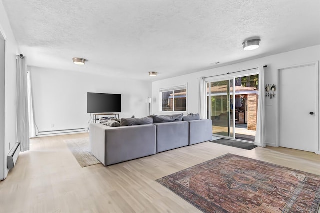 7715 236th St SW, Edmonds, WA 98026 - living room featuring baseboard heating, a textured ceiling, light wood-type flooring, and a baseboard heating unit