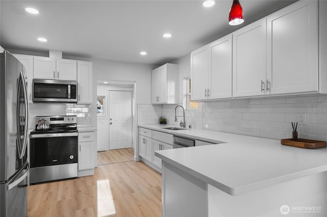 3514 S Tyler St, Tacoma, WA 98409 - kitchen featuring appliances with stainless steel finishes, a sink, light countertops, light wood-style flooring, and backsplash