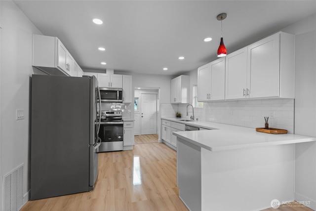 3514 S Tyler St, Tacoma, WA 98409 - kitchen featuring stainless steel appliances, a sink, a peninsula, light wood-style floors, and white cabinets
