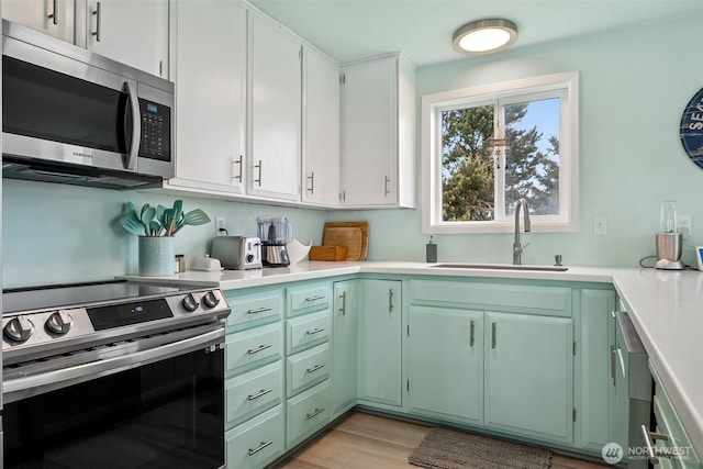 177 N Razor Clam Dr SW, Ocean Shores, WA 98569 - kitchen with appliances with stainless steel finishes, a sink, light countertops, green cabinets, and light wood finished floors