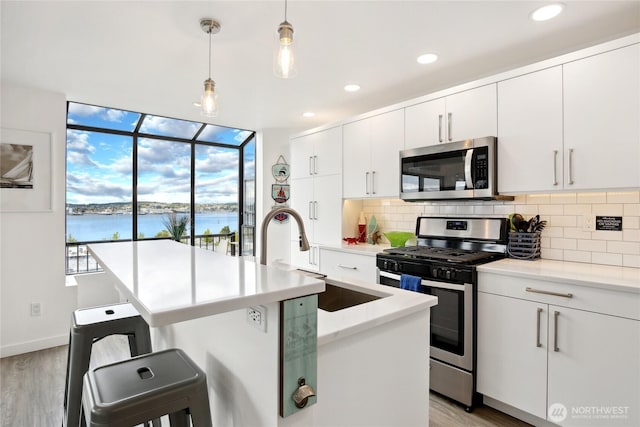 817 Kitsap St, Port Orchard, WA 98366 - kitchen with appliances with stainless steel finishes, a sink, a water view, backsplash, and light wood-style flooring