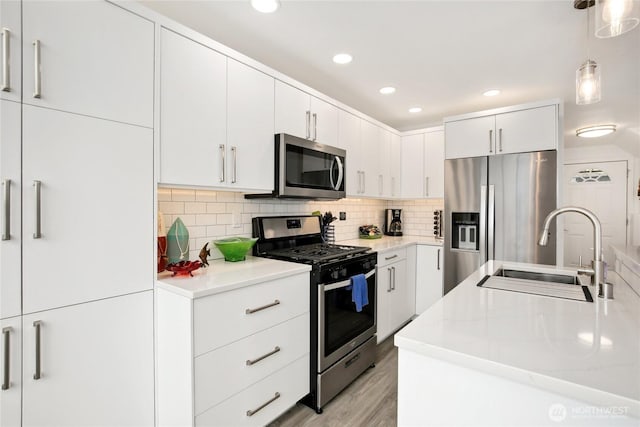 817 Kitsap St, Port Orchard, WA 98366 - kitchen featuring appliances with stainless steel finishes, a sink, pendant lighting, light countertops, and light wood finished floors