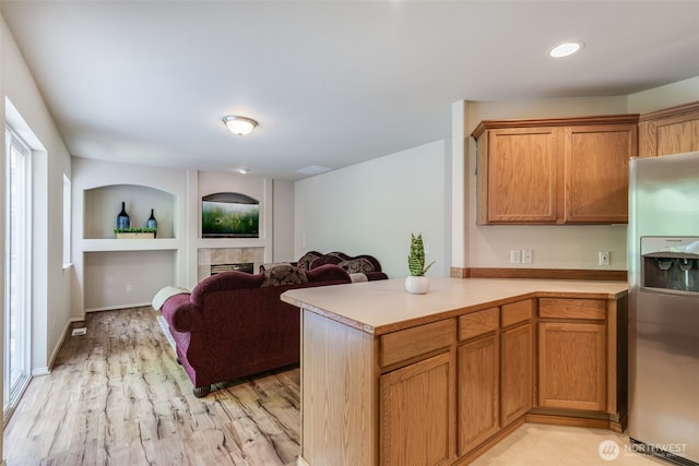 11710 SE 310th St, Auburn, WA 98092 - kitchen featuring stainless steel refrigerator with ice dispenser, light countertops, light wood finished floors, brown cabinets, and a tiled fireplace