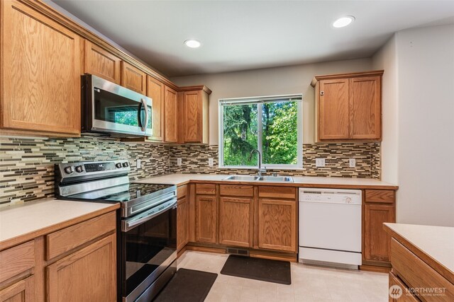 11710 SE 310th St, Auburn, WA 98092 - kitchen with appliances with stainless steel finishes, a sink, light countertops, decorative backsplash, and recessed lighting