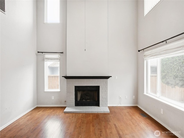1015 SW 348th Pl, Federal Way, WA 98023 - unfurnished living room with wood finished floors, plenty of natural light, a brick fireplace, baseboards, and a towering ceiling