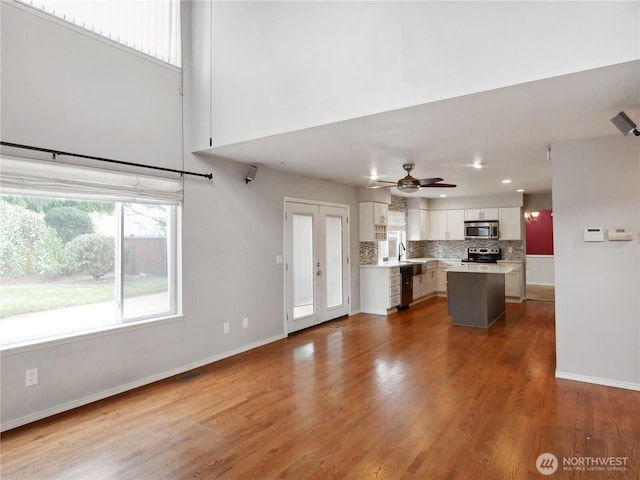 1015 SW 348th Pl, Federal Way, WA 98023 - kitchen featuring appliances with stainless steel finishes, white cabinets, light countertops, tasteful backsplash, and wood finished floors
