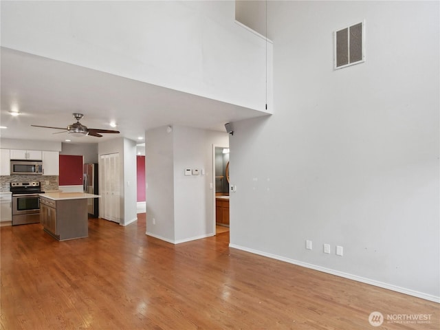 1015 SW 348th Pl, Federal Way, WA 98023 - kitchen featuring appliances with stainless steel finishes, white cabinets, light countertops, open floor plan, and tasteful backsplash