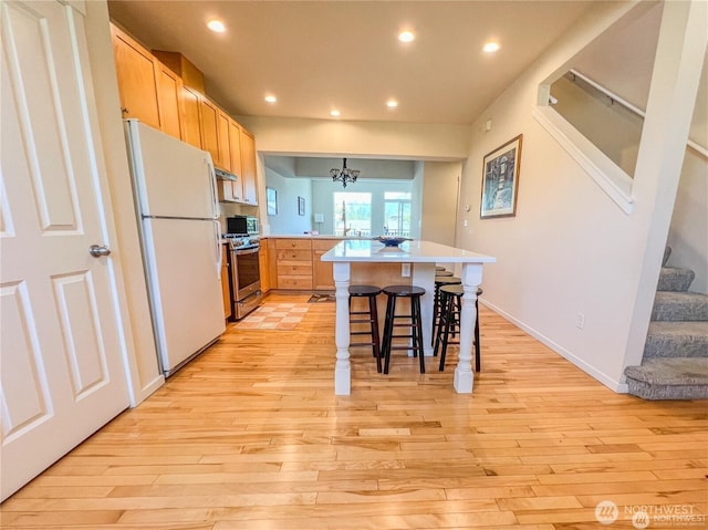 7732 Fairway Ave SE Unit 203, Snoqualmie, WA 98065 - kitchen with freestanding refrigerator, a peninsula, stainless steel gas stove, light wood-style floors, and recessed lighting