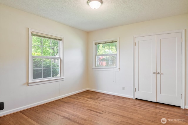 1515 19th Ave, Longview, WA 98632 - unfurnished bedroom featuring light wood-type flooring, multiple windows, baseboards, and a textured ceiling