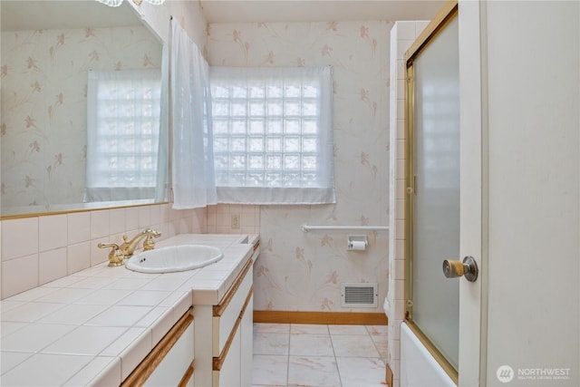 1515 19th Ave, Longview, WA 98632 - bathroom featuring vanity, wallpapered walls, marble look tiles, shower / bath combination with glass door, and baseboards