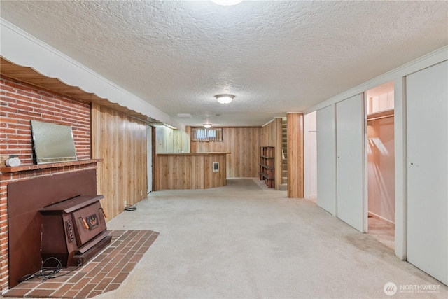 1515 19th Ave, Longview, WA 98632 - basement featuring a wood stove, wood walls, carpet flooring, and a textured ceiling