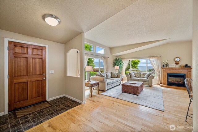 2570 Island View Ln, Lummi Island, WA 98262 - foyer entrance featuring lofted ceiling, a textured ceiling, hardwood / wood-style flooring, baseboards, and a glass covered fireplace