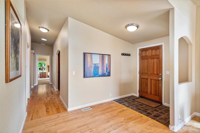 2570 Island View Ln, Lummi Island, WA 98262 - entrance foyer featuring wood finished floors, arched walkways, baseboards, and a textured ceiling