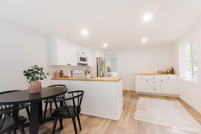 3333 228th St Unit 42, Bothell, WA 98021 - kitchen featuring white appliances, butcher block counters, a peninsula, white cabinets, and light wood finished floors