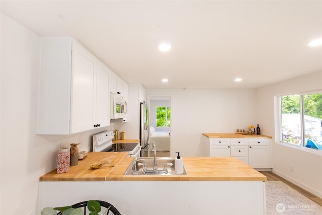 3333 228th St Unit 42, Bothell, WA 98021 - kitchen featuring white appliances, wood counters, a peninsula, light wood-type flooring, and white cabinets