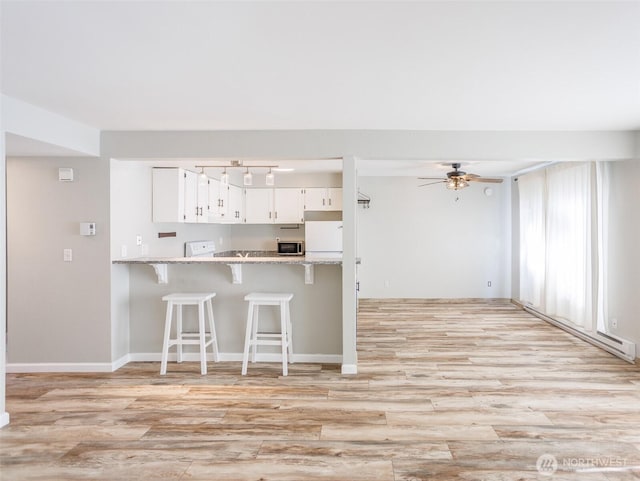 821 Essex Pl NE Unit 1-B, Lacey, WA 98516 - kitchen with a ceiling fan, fridge, light countertops, light wood-type flooring, and a kitchen bar