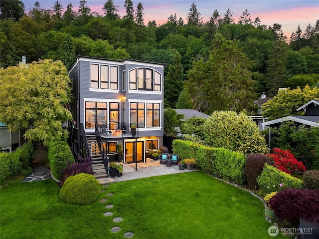 4864 Rockaway Beach Rd NE, Bainbridge Island, WA 98110 - back of property at dusk with stairway, a patio, a lawn, and a wooden deck