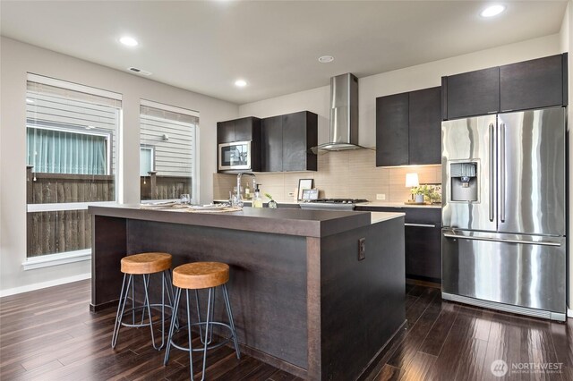5614 Douglas Ave SE, Auburn, WA 98092 - kitchen featuring appliances with stainless steel finishes, wall chimney range hood, dark wood finished floors, a kitchen bar, and recessed lighting