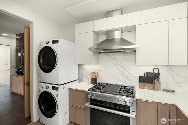 999 110th Ave NE Unit 600, Bellevue, WA 98004 - kitchen with wall chimney range hood, stainless steel gas stove, stacked washer / dryer, tasteful backsplash, and modern cabinets