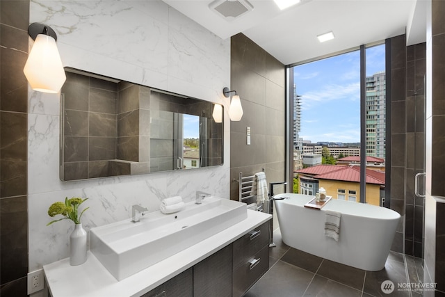 999 110th Ave NE Unit 600, Bellevue, WA 98004 - full bathroom featuring tile walls, a freestanding bath, vanity, tile patterned flooring, and a view of city