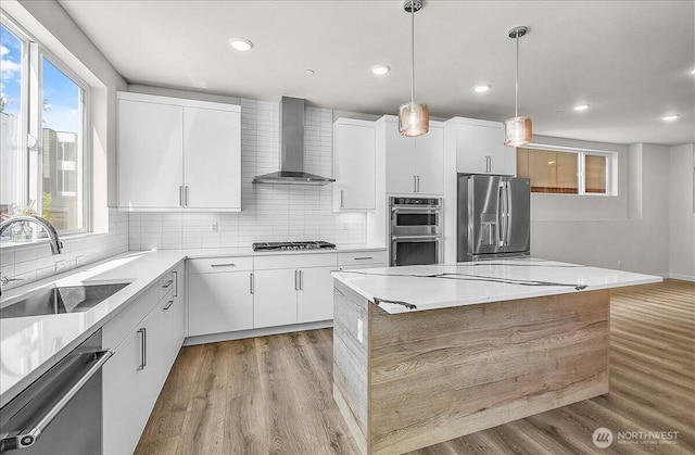 8922 NE 173rd Pl Unit A, Bothell, WA 98011 - kitchen featuring stainless steel appliances, wall chimney range hood, light wood finished floors, backsplash, and recessed lighting