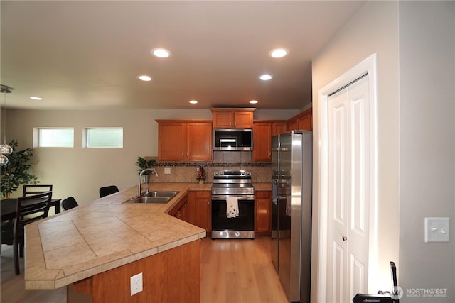 26133 242nd Ave SE, Maple Valley, WA 98038 - kitchen with appliances with stainless steel finishes, a sink, a peninsula, brown cabinets, and recessed lighting