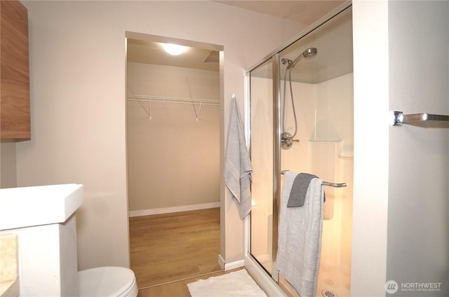 26133 242nd Ave SE, Maple Valley, WA 98038 - full bath featuring a shower stall, wood finished floors, toilet, a walk in closet, and baseboards