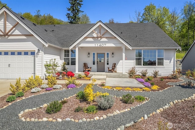 11407 73rd Ave NE, Arlington, WA 98223 - view of front of home featuring an attached garage, covered porch, a shingled roof, and concrete driveway