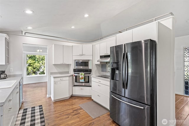 26005 225th Ct SE, Maple Valley, WA 98038 - kitchen with stainless steel appliances, under cabinet range hood, light countertops, light wood-type flooring, and recessed lighting