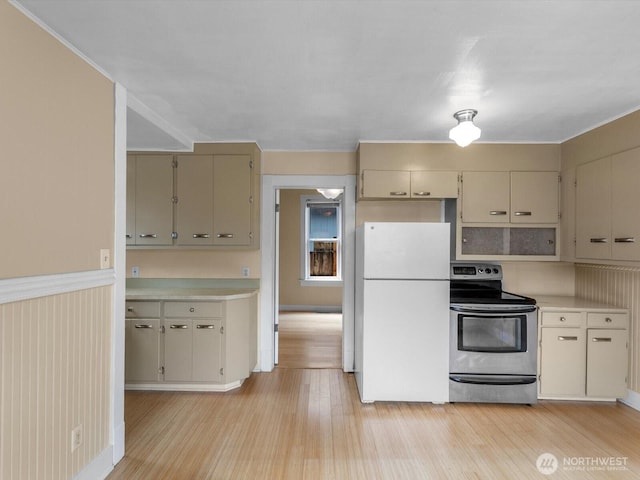 4116 25th Ave SW, Seattle, WA 98106 - kitchen with stainless steel electric range oven, freestanding refrigerator, light wood-style flooring, light countertops, and cream cabinetry