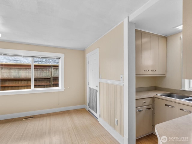 4116 25th Ave SW, Seattle, WA 98106 - kitchen with a sink, light wood finished floors, light countertops, baseboards, and cream cabinetry